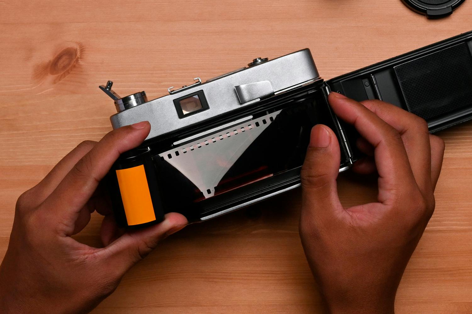 Isättning av film. Sätt in filmrullen på ena sidan och kläm fast filmremsans ände på den andra sidan.